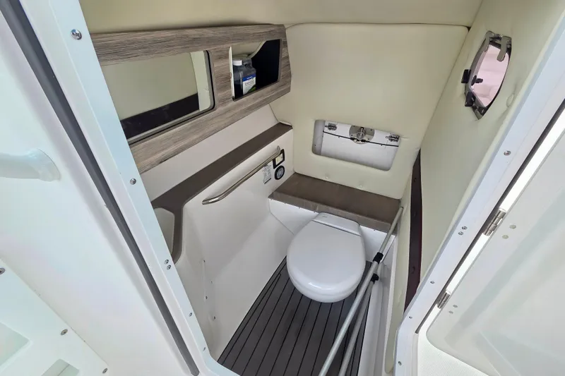 Slide: The Image of 2022 Edgewater 248 CX boat interior with compact bathroom, featuring a toilet and mirror. - 12