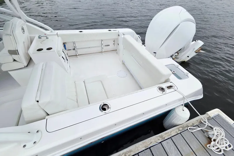 Slide: The Image of Edgewater 248 CX 2022 boat interior with seating and motor, docked on calm water. - 15