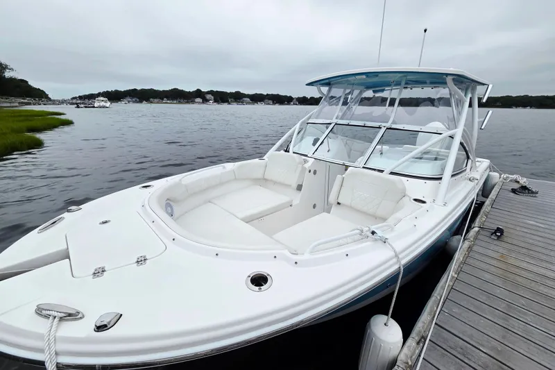 Slide: The Image of 2022 Edgewater 248 CX boat docked on a calm lake under cloudy skies. - 2