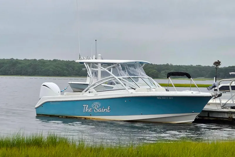 Slide: The Image of 2022 Edgewater 248 CX boat named "The Saint" docked on a calm lake. - 3