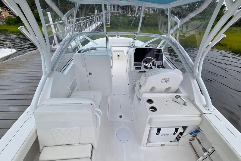 Slide: The Image of 2022 Edgewater 248 CX boat interior with helm, seating, and console, docked by the water. - 7