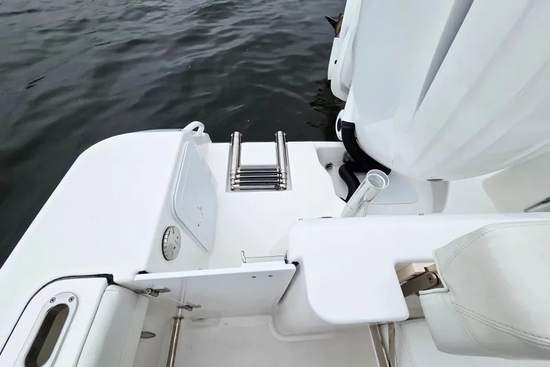 Slide: The Image of 2022 Edgewater 248 CX boat stern with swim ladder and seating, on calm water. - 8