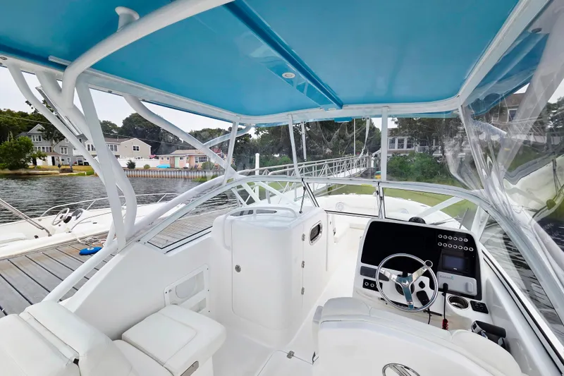 Slide: The Image of 2022 Edgewater 248 CX boat interior with blue canopy, docked by waterfront homes. - 9