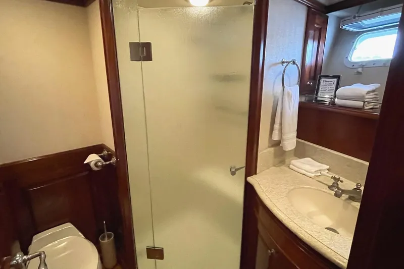 Slide: The Image of Luxurious 2001 Rayburn Flush Deck yacht interior with wood finish, featuring helm and bathroom. - 15