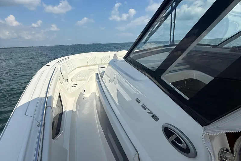 Slide: The Image of 2022 Pursuit S 378 Sport boat cruising on open water under a clear sky. - 12
