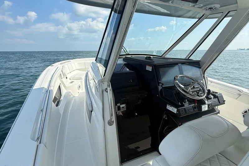 Slide: The Image of 2022 Pursuit S 378 Sport boat interior with helm, ocean view, and clear skies. - 38