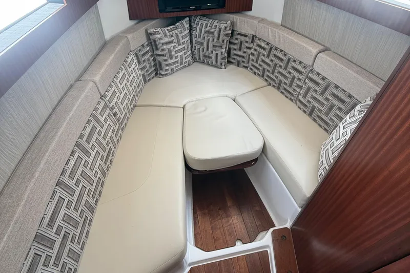 Slide: The Image of 2022 Pursuit S 378 Sport cabin with cushioned seating and patterned pillows. - 54