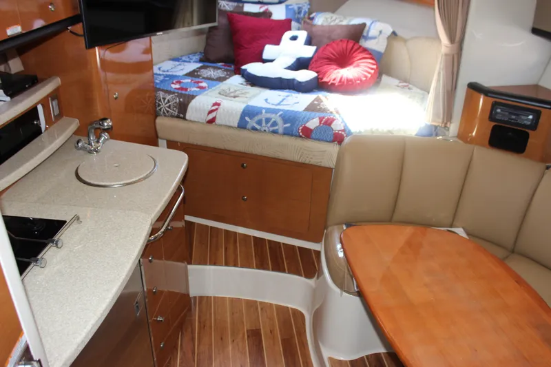 Slide: The Image of 2007 Chaparral Signature 310 interior with cozy seating, kitchenette, and nautical-themed bedding. - 10