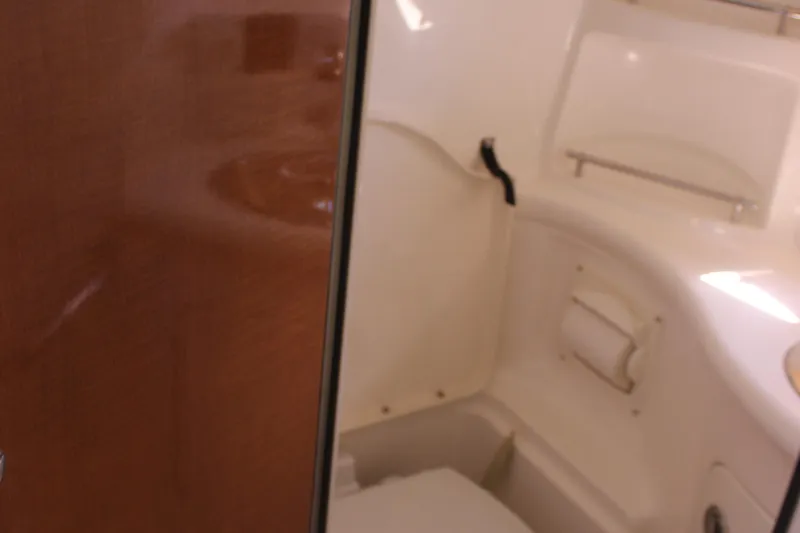 Slide: The Image of 2007 Chaparral Signature 310 boat interior bathroom with wooden door and white fixtures. - 23