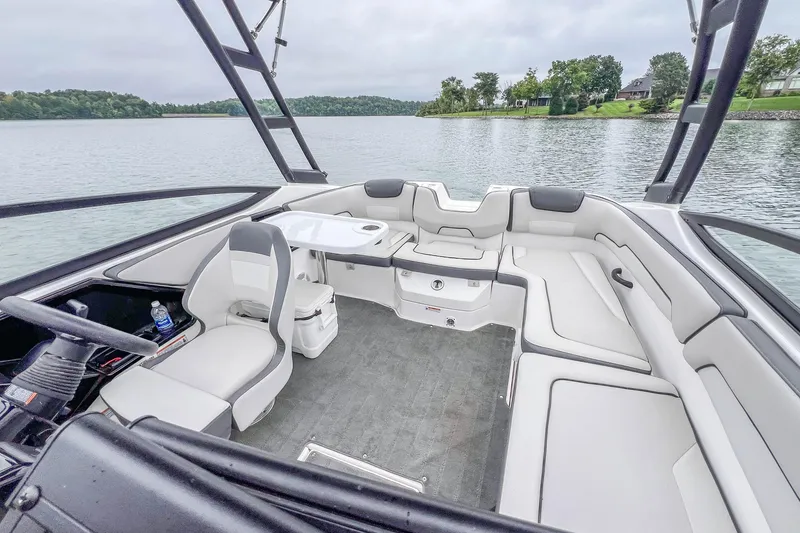 Slide: The Image of 2023 Yamaha Boats AR190 interior with seating and steering, on a calm lake. - 14