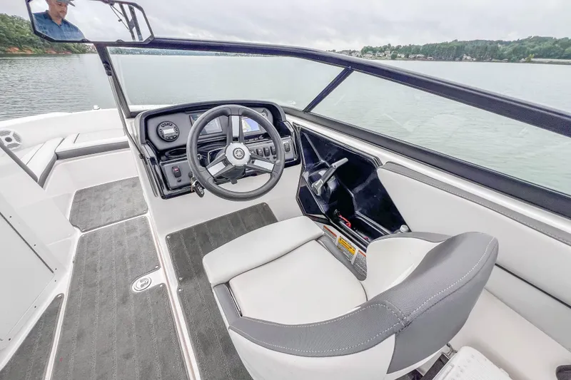 Slide: The Image of 2023 Yamaha Boats AR190 cockpit with steering wheel and controls on a calm lake. - 17