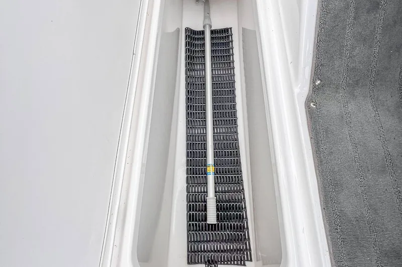 Slide: The Image of 2023 Yamaha AR190 boat storage compartment with black mat and gray carpet. - 26