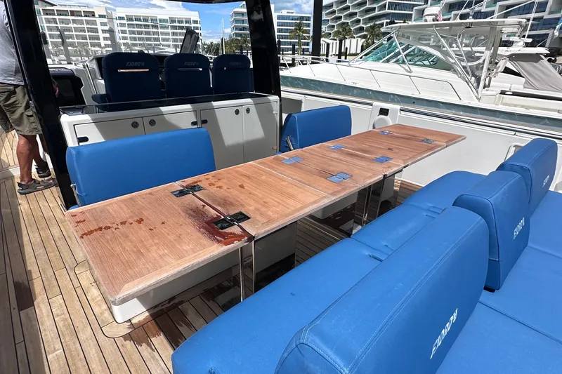Slide: The Image of Luxury seating area on 2020 Fjord 44 Open yacht with blue cushions and wooden table. - 12