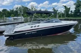 Slide: The Image of 2014 Larson LXi 258 IO boat on calm water, under a partly cloudy sky. - 1