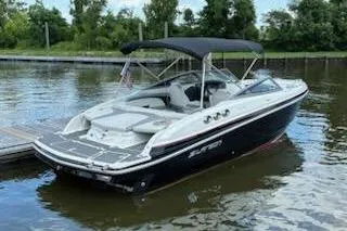 Slide: The Image of 2014 Larson LXi 258 IO boat docked on a calm lake with lush greenery. - 9