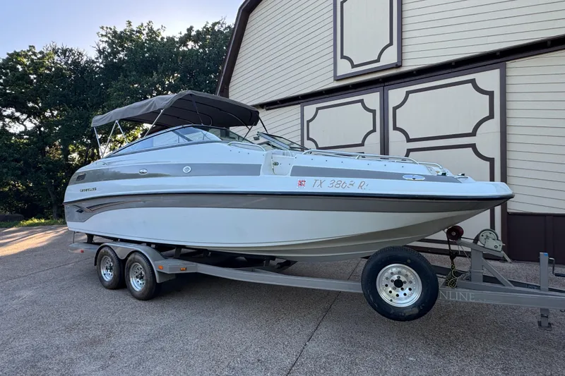 Slide: The Image of 2002 Crownline 239 DB boat on calm water under a partly cloudy sky. - 2