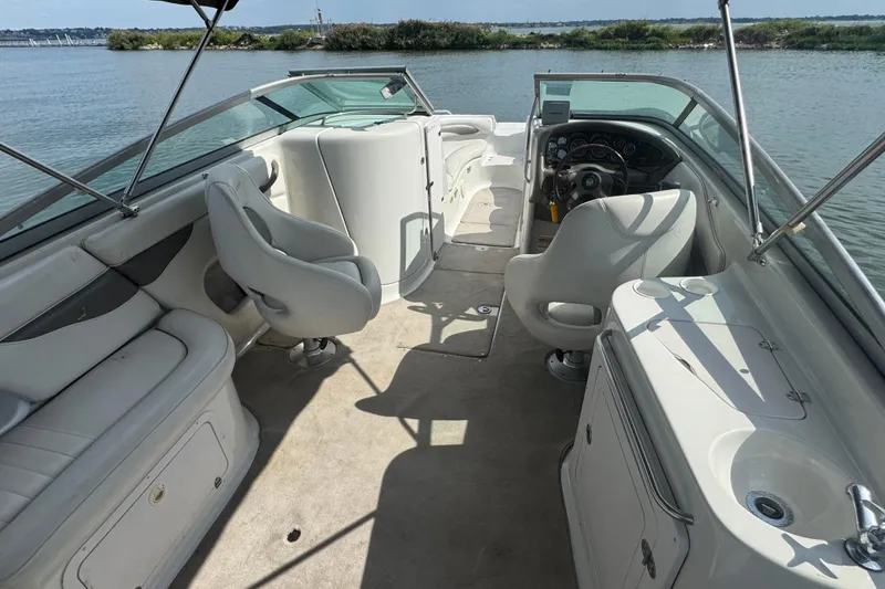 Slide: The Image of 2002 Crownline 239 DB boat interior with seating and steering, docked by the water. - 23