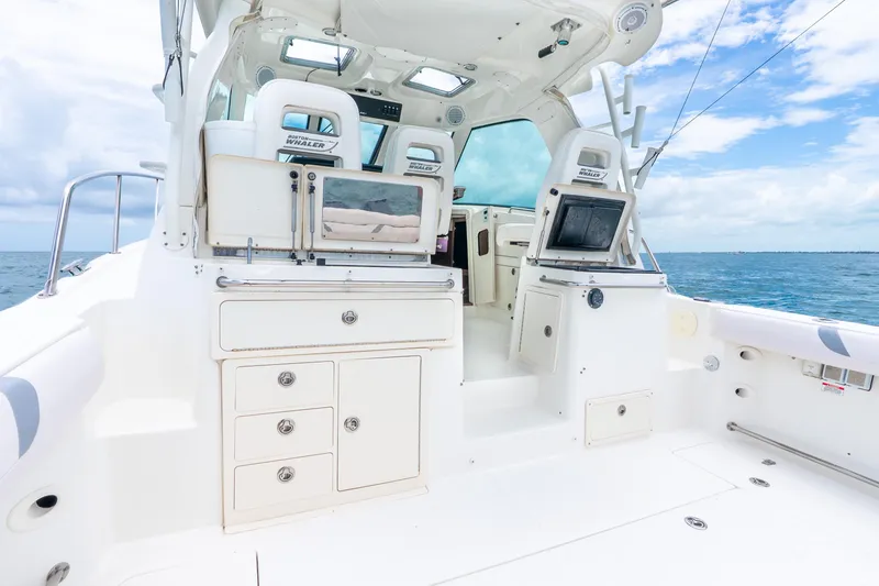 Slide: The Image of 2012 Boston Whaler 345 Conquest boat interior with ocean view, featuring white cabinetry and seating. - 39