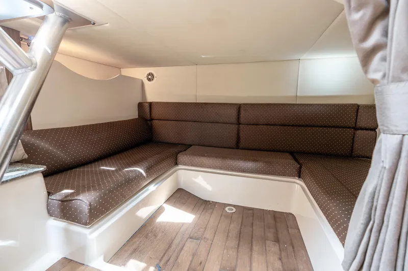 Slide: The Image of 2012 Boston Whaler 345 Conquest cabin interior with brown cushioned seating and wood flooring. - 49