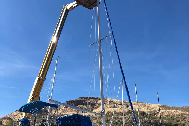 Slide: The Image of Crane lifting mast of 1996 Catalina 30 MkIII sailboat against clear blue sky. - 25