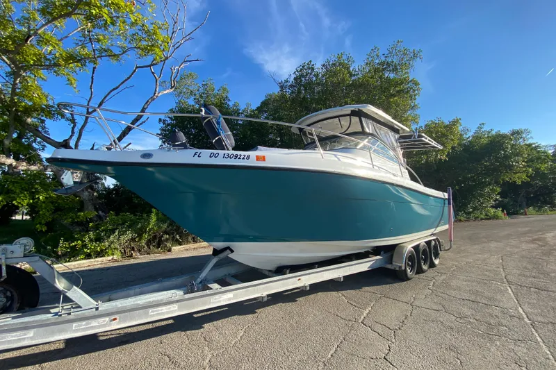 Slide: The Image of 2009 Century 3200 Offshore boat on trailer, parked outdoors under clear blue sky. - 2