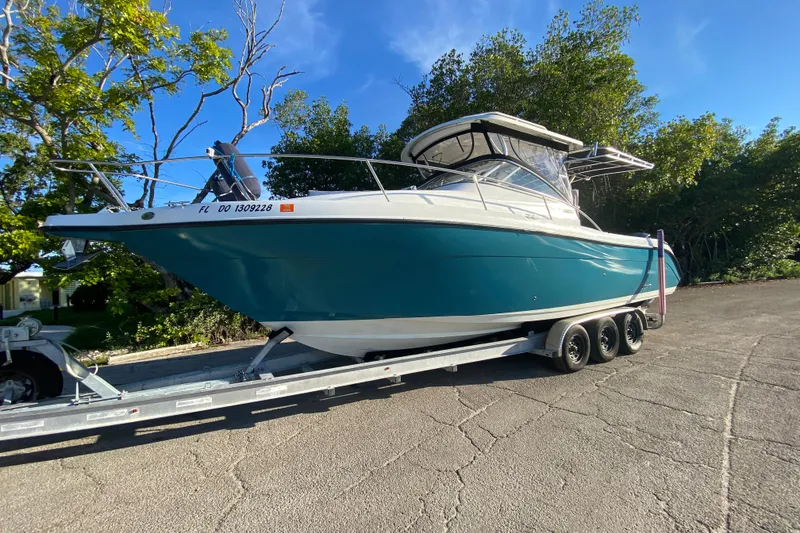 Slide: The Image of 2009 Century 3200 Offshore boat on trailer, parked outdoors under clear blue sky. - 33