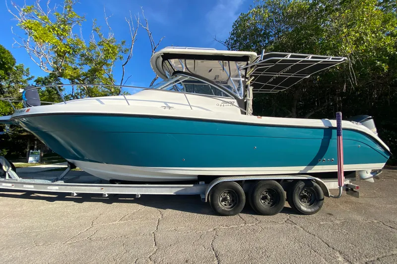 Slide: The Image of 2009 Century 3200 Offshore boat on trailer, parked outdoors, under clear blue sky. - 4