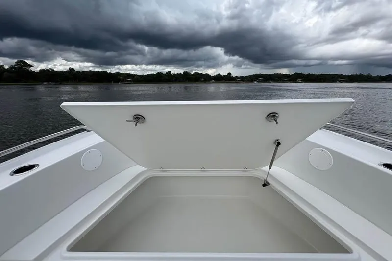 Slide: The Image of 2026 Parker 18SE Center Console boat with open storage compartment under cloudy sky. - 16
