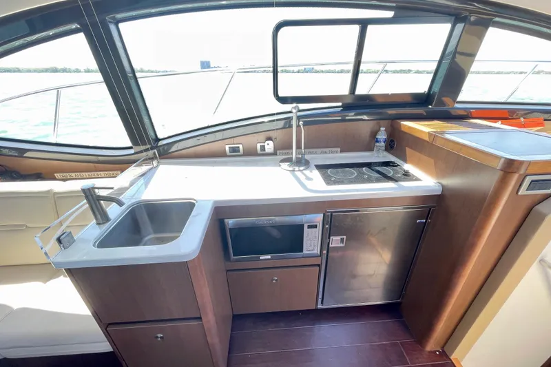 Slide: The Image of 2017 Sea Ray Sundancer 400 yacht kitchen with sink, stove, microwave, and scenic window view. - 14