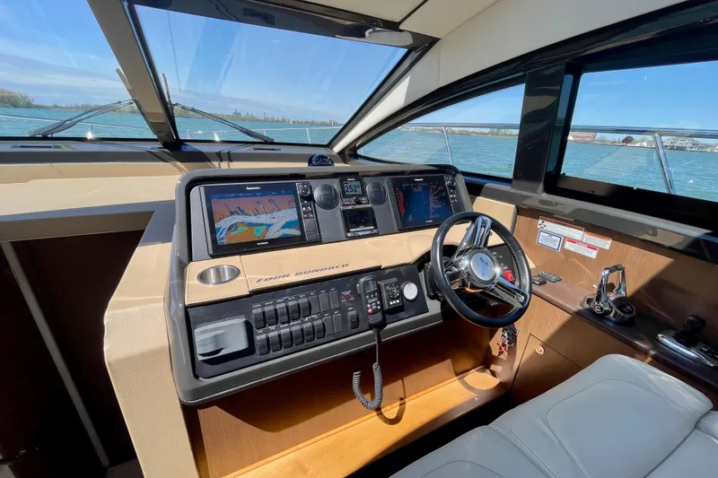 Slide: The Image of 2017 Sea Ray Sundancer 400 helm with navigation screens and steering wheel, overlooking water. - 18