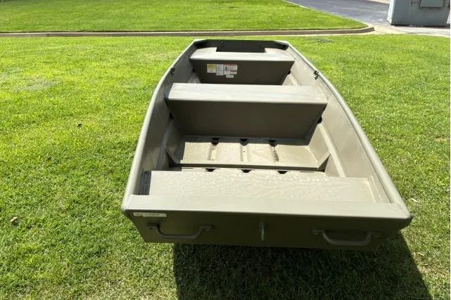 Slide: The Image of 2026 Tracker Grizzly 14 Jon boat on grass, showcasing interior seating and storage. - 2