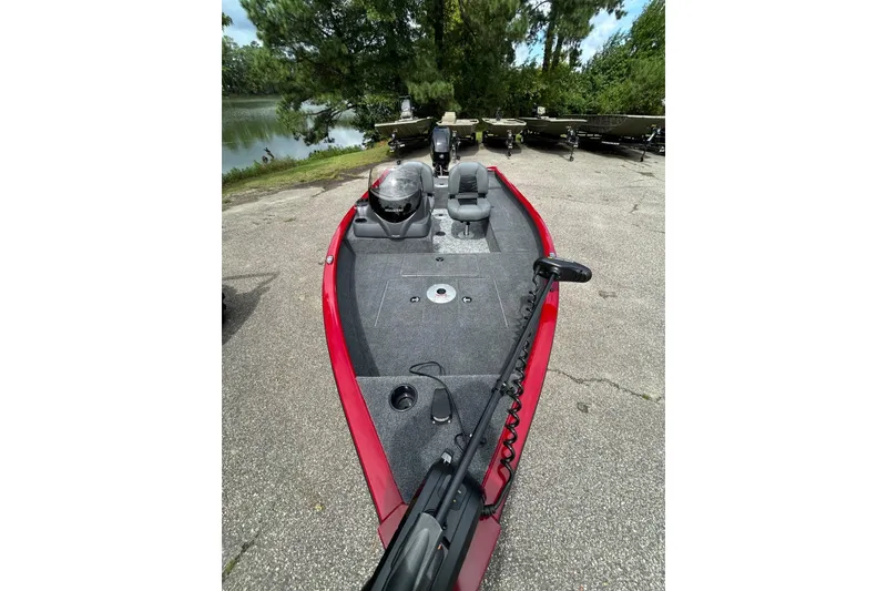 Slide: The Image of 2026 Tracker Super Guide V-16 SC boat with red trim, parked near a lake. - 44