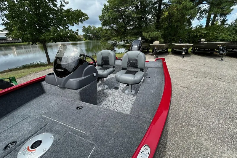 Slide: The Image of 2026 Tracker Super Guide V-16 SC boat with gray seating, red trim, and lake backdrop. - 48