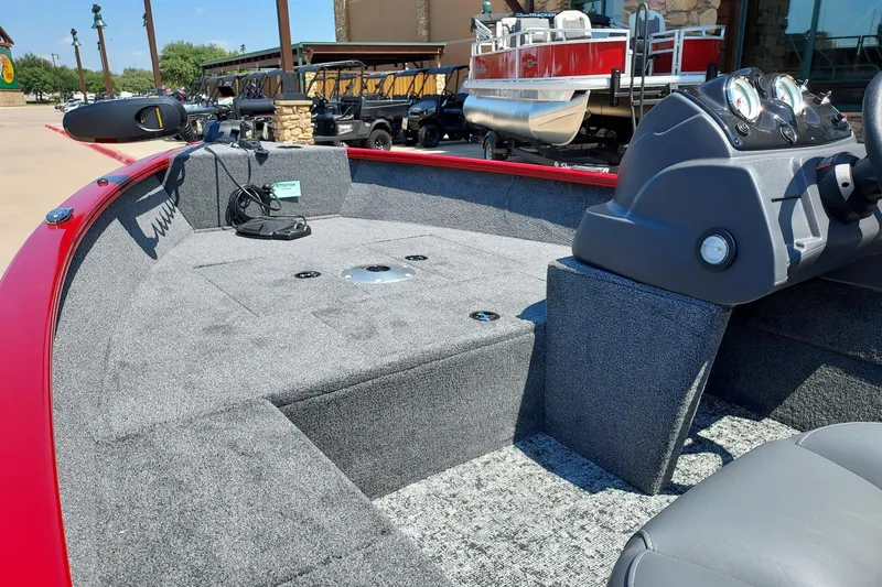 Slide: The Image of 2026 Tracker Super Guide V-16 SC boat interior with gray carpet and red trim. - 2