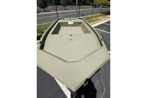 Slide: The Image of 2026 Tracker Grizzly 1754 Utility boat in a parking lot, showcasing its spacious deck. - 2