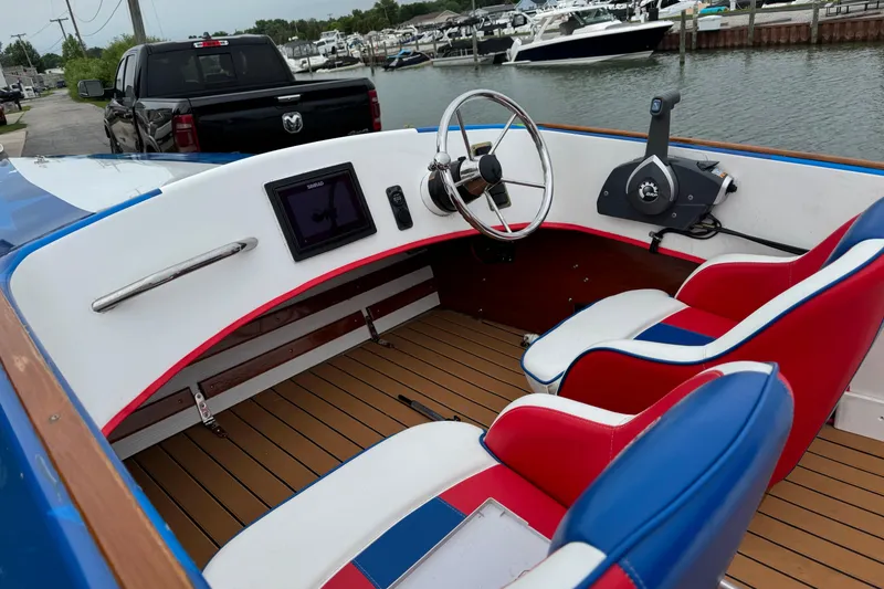 Slide: The Image of Interior of a custom 2021 boat with red, white, and blue seating, docked near water. - 13