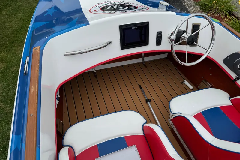 Slide: The Image of Custom 2021 boat interior with red, white, and blue seating, wooden floor, and steering wheel. - 16