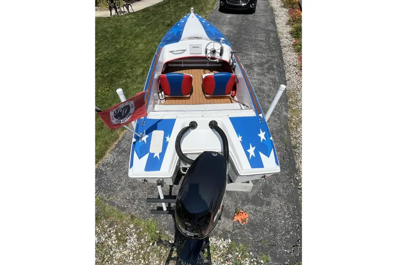 Slide: The Image of 2021 Patriot boat with star-spangled design, red and blue seats, and outboard motor. - 6