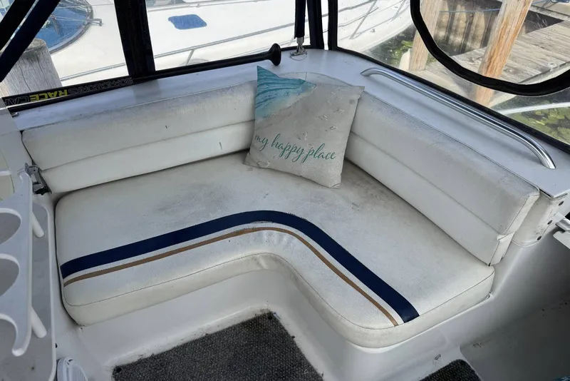 Slide: The Image of 1998 Mainship 31 Sedan Bridge interior with white seating and decorative pillow. - 14