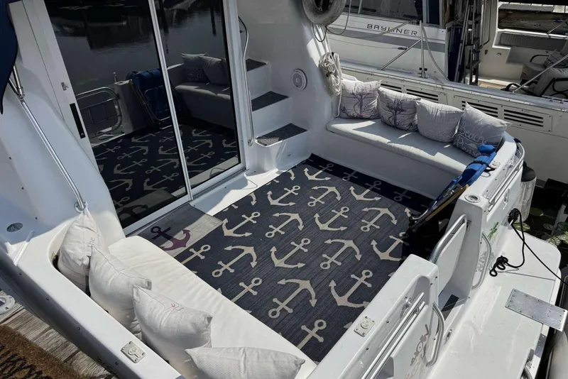 Slide: The Image of 1998 Mainship 31 Sedan Bridge boat deck with anchor-themed rug and cushioned seating. - 17