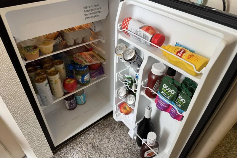 Slide: The Image of Mini fridge stocked with drinks, condiments, and snacks on a 1998 Mainship 31 Sedan Bridge. - 21