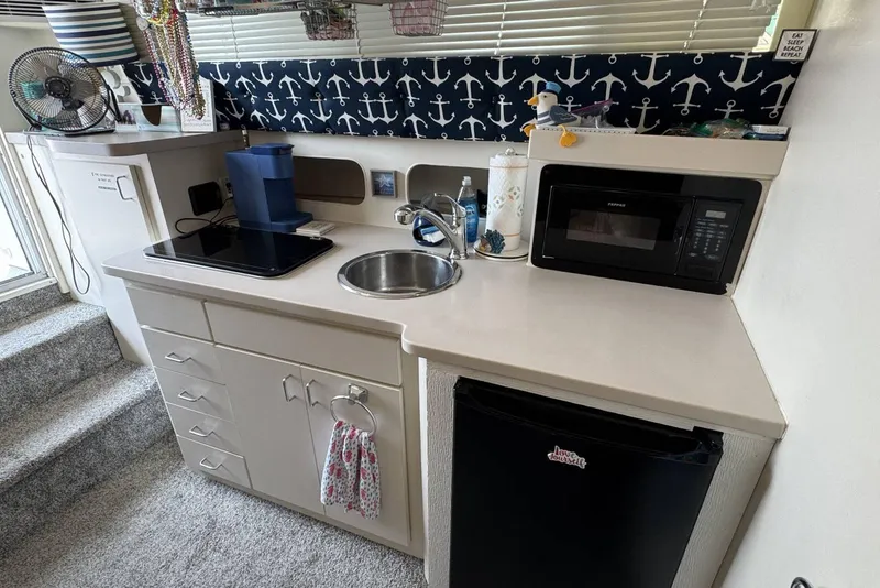 Slide: The Image of 1998 Mainship 31 Sedan Bridge kitchen with sink, microwave, and nautical decor. - 23