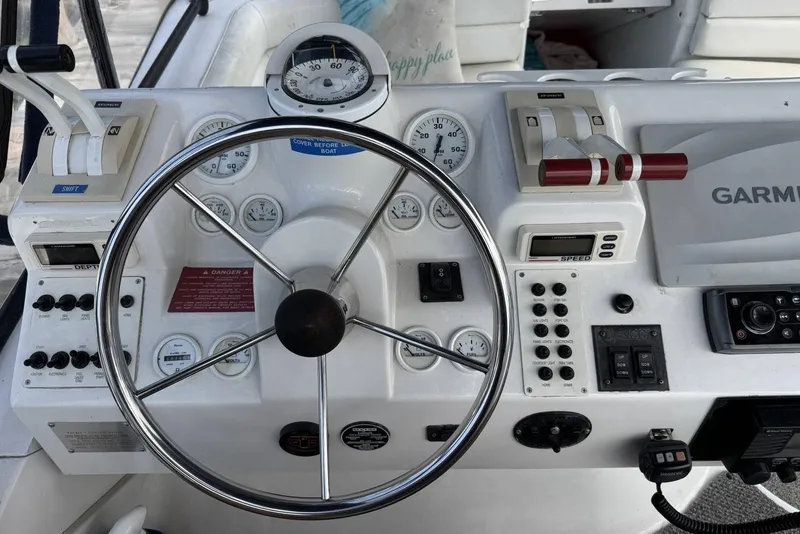 Slide: The Image of 1998 Mainship 31 Sedan Bridge helm with steering wheel, gauges, and navigation controls. - 9