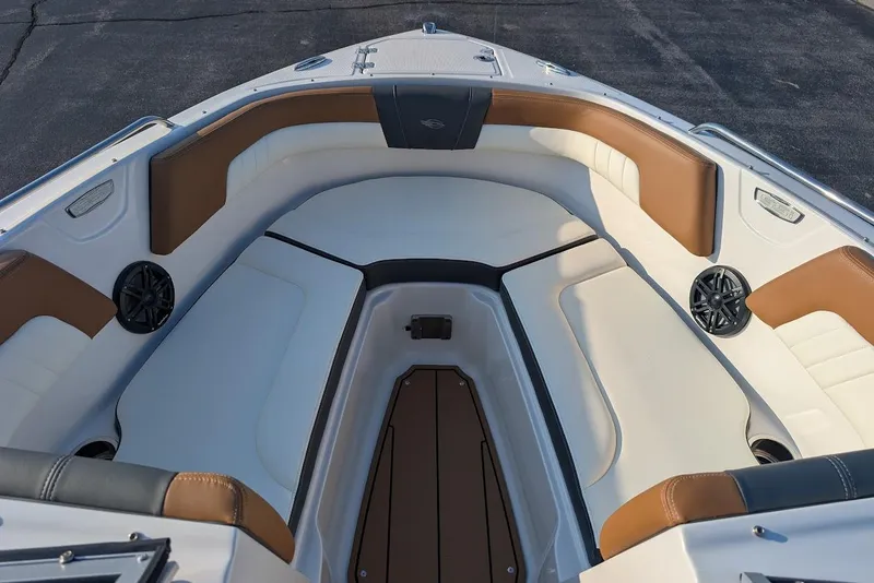 Slide: The Image of 2023 Chaparral 23 SSi boat interior with white and brown seating, speakers, and storage. - 16
