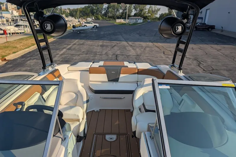 Slide: The Image of 2023 Chaparral 23 SSi boat interior with seating and speakers, docked at marina. - 17