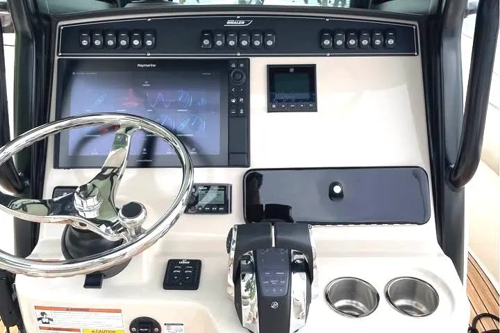 Slide: The Image of 2021 Boston Whaler 250 Outrage dashboard with steering wheel, controls, and navigation screens. - 6
