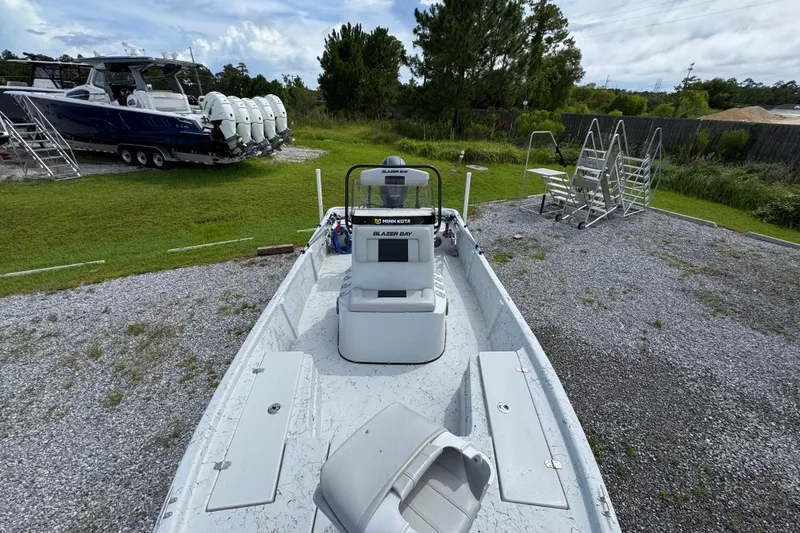 Slide: The Image of 2018 Blazer Bay 2170 boat on gravel, with green grass and trees in the background. - 19