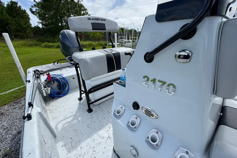 Slide: The Image of 2018 Blazer Bay 2170 boat interior with seating and equipment, parked on grass. - 22