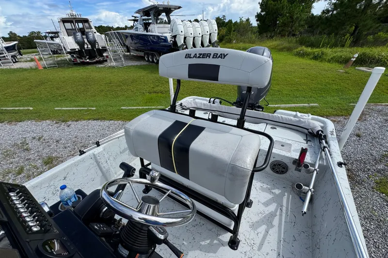 Slide: The Image of 2018 Blazer Bay 2170 boat interior with steering wheel and seating, parked on grass. - 23