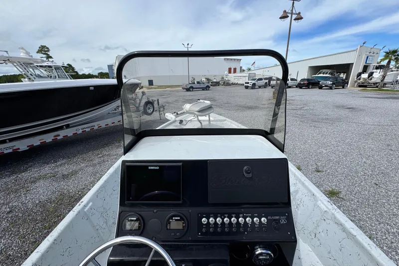 Slide: The Image of 2018 Blazer Bay 2170 boat dashboard with controls and windshield in a marina setting. - 26
